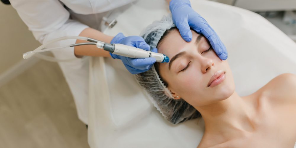View from above rejuvenation of beautiful woman enjoying cosmetology procedures in beauty salon. Dermatology, hands in blue glows, healthcare, therapy, botox