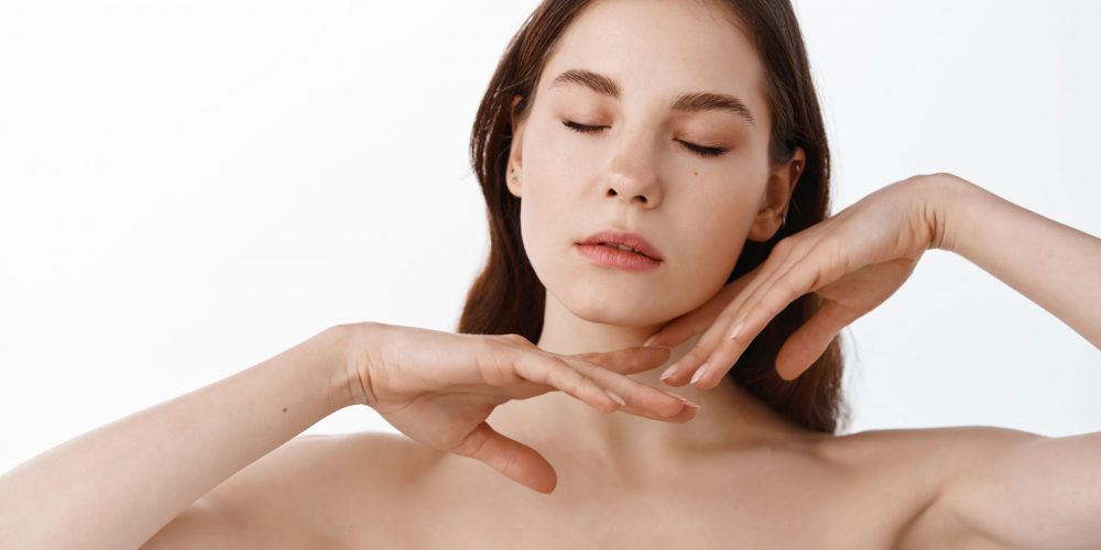 Beautiful Young Woman with Clean Fresh Skin touch own face . Facial treatment . Cosmetology, beauty and spa.
